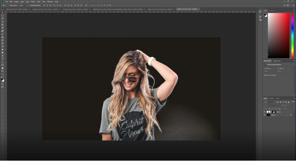 Una donna sorridente con lunghi capelli biondi e occhiali da sole è in piedi su uno sfondo scuro. Indossa una maglietta grigia e si tocca i capelli con una mano. L'interfaccia di Photoshop, ideale per scontornare i capelli, è visibile attorno all'immagine.