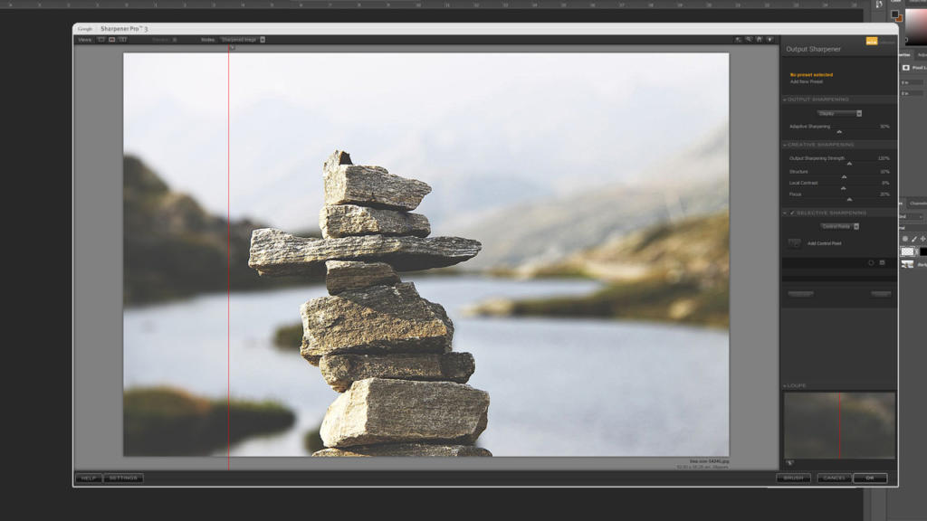 Una pila di pietre in equilibrio è al centro dell'immagine contro uno sfondo sfocato di acqua e colline. La scena appare su un'interfaccia software di fotoritocco, migliorata tramite Google Nik Collection, con strumenti di modifica visibili sul lato destro dello schermo.