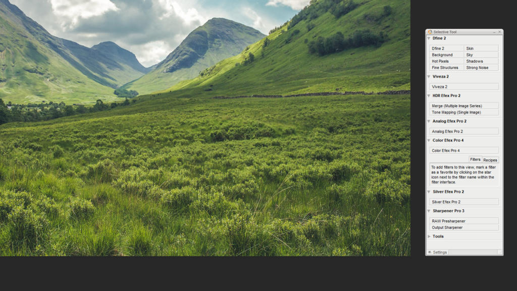 Una valle verdeggiante con dolci colline sotto un cielo nuvoloso si estende pacificamente. Il paesaggio mostra diverse tonalità di verde fogliame ed erba. Sulla destra, una barra degli strumenti parzialmente visibile accenna alla magia delle opzioni di modifica di Google Nik Collection che esaltano questa vista serena.
