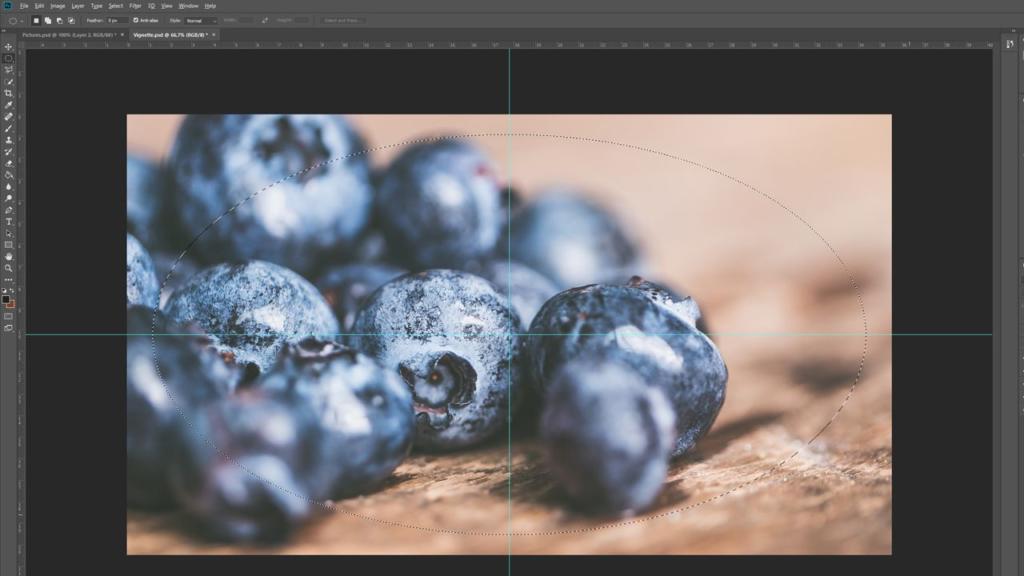 Immagine di mirtilli su una superficie di legno visualizzata sullo schermo di un computer. L'immagine, aperta in un programma di editing con linee guida e barre degli strumenti visibili, presenta una sottile vignettatura in Photoshop, che sfoca delicatamente il primo piano e lo sfondo per un effetto mirato.