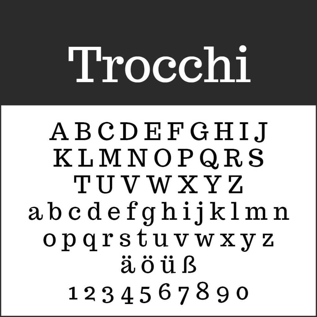 Un esempio di font serif con Trocchi in alto presenta una raccolta di caratteri facili da leggere: lettere maiuscole dalla A alla Z, lettere minuscole dalla a alla z, caratteri speciali Ä, Ö, Ü, ß e numeri da 0 a 9 in stile classico su sfondo bianco.