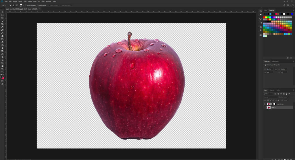 Una mela rosso brillante, luccicante di gocce d'acqua, è visualizzata su uno sfondo trasparente. L'immagine, aperta in un software di editing come Photoshop, invita alla creatività con le sue tavolozze di colori e gli strumenti pronti ad attenuare i bordi per una finitura lucida.