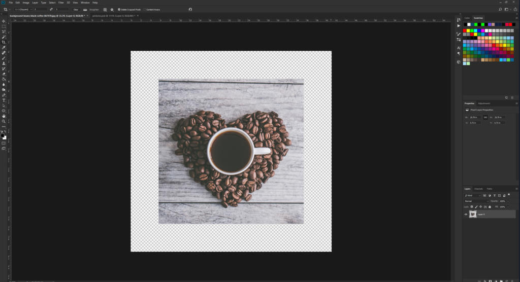 Una tazza di caffè piena di caffè è appoggiata su una disposizione di chicchi a forma di cuore su una superficie di legno. Visualizzata su uno schermo di modifica delle foto, l'immagine ti invita a ritagliare l'immagine in Photoshop, utilizzando gli strumenti di modifica circostanti e le tavolozze di colori per la perfezione.