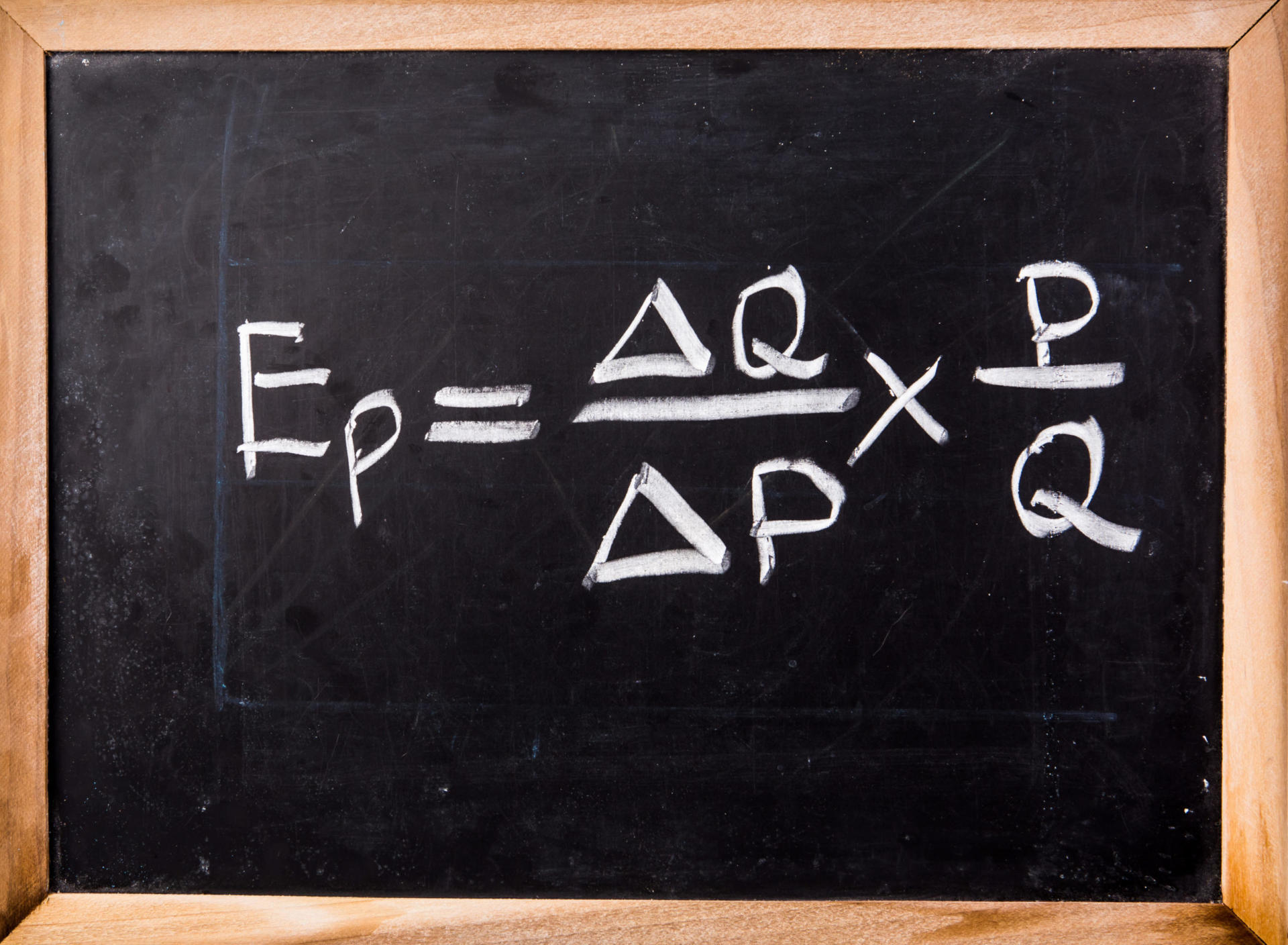 Una lavagna mostra la formula dell'elasticità della domanda al prezzo, o "elasticità del prezzo": Ep = (ΔQ / ΔP) x (P / Q), dove Ep indica l'elasticità, ΔQ è la variazione della quantità, ΔP è la variazione del prezzo, P è il prezzo e Q è la quantità.