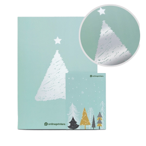Una borsa regalo verde menta raffigurante un albero di Natale argentato con una stella in cima. C'è un inserto circolare ravvicinato dell'albero. Sotto, una cartolina mostra diversi alberi colorati e stilizzati. Entrambi gli articoli hanno il logo di onlineprinters.